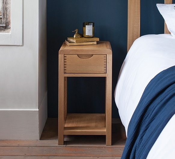 Ercol Bosco compact oak bedside table with drawer and shelf in bedroom interior